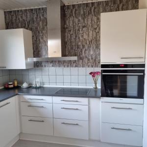 a kitchen with white cabinets and a black oven at Joysha's House in Ikast