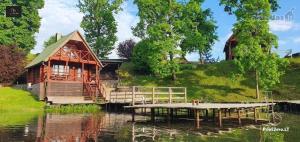 a house on the water with a dock in front of it at Ežero Panorama in Skirlėnai