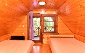 two beds in a wooden room with a window at Ežero Panorama in Skirlėnai