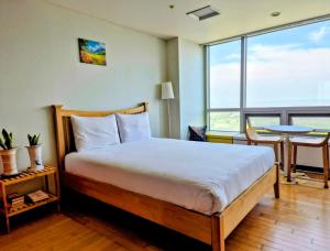 a bedroom with a bed and a table and a large window at Cozy - Sunny Studio in Incheon