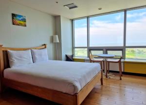 a bedroom with a bed and a table and windows at Cozy - Sunny Studio in Incheon