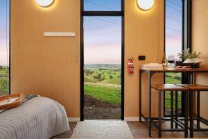 a bedroom with a bed and a glass door with a view at Belrose Estate by Tiny Away in Dumbalk