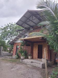 a wooden house with a balcony and a palm tree at Beachfront AC Cave Cabin for 10pax in Caba