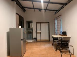 a kitchen with a refrigerator and a table and chairs at โรงแรมควีนส์ (Queen) in Ban Tha Kham