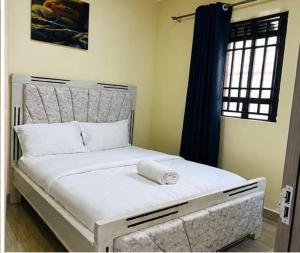 a bedroom with a white bed with a window at Rosebank Villas in Luanda