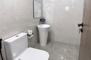 a bathroom with a white toilet and a sink at Rosebank Villas in Luanda