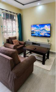a living room with two couches and a flat screen tv at Rosebank Villas in Luanda