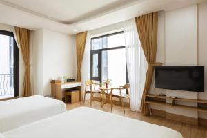 a hotel room with two beds and a flat screen tv at Thai Thinh Hotel Grand World in Phú Quốc