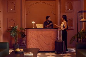 a man and a woman standing at a counter in a lobby at Minimalist - Lake Pichola Edit in Udaipur