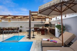 an outdoor patio with a swimming pool and an umbrella at Pervolia House Private Pool Near Airport in Kremasti