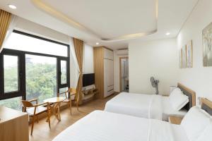 a hotel room with two beds and a table and chairs at Thai Thinh Hotel Grand World in Phú Quốc
