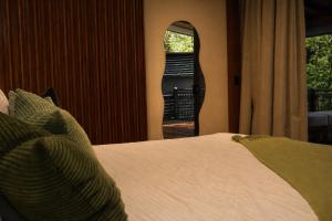 a bedroom with a bed and a mirror and a window at Nuakú Jungle in Aguas Zarcas
