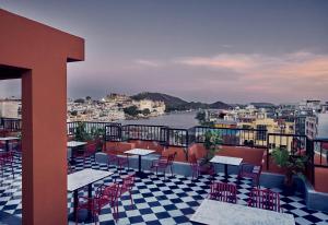 a balcony with tables and chairs and a view of the water at Minimalist - Lake Pichola Edit in Udaipur