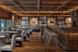 a restaurant with tables and chairs and a bar at Miiro The Mansard in Gstaad