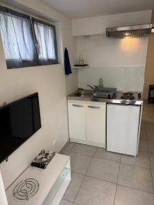 a kitchen with white cabinets and a flat screen tv at Résidence Villa Landes in Gien