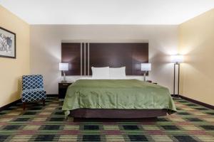 a hotel room with a bed and a chair at Quality Inn Cadiz in Cadiz +23 photos