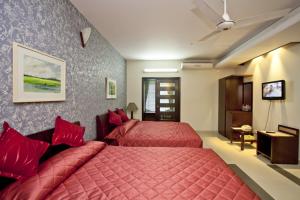 a bedroom with two beds with red pillows at Well Park Residence in Chittagong