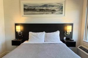 ein Schlafzimmer mit einem Bett mit zwei Nachttischen und einem Gemälde in der Unterkunft Quality Inn in Nanaimo + 19 Fotos