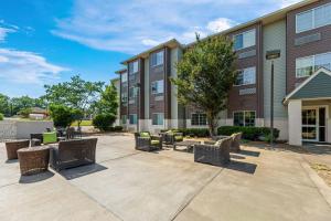 a courtyard with chairs and tables in front of a building at Clarion Pointe Starkville near University in Starkville