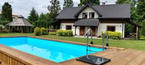 a house with a swimming pool in front of a house at Chaty Gajowego w Bieszczadach z basenem 517-665-624 in Bukowiec