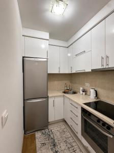 a kitchen with white cabinets and a stainless steel refrigerator at Apartments Sarajevo Nova Otoka in Sarajevo