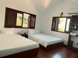 two beds in a room with two windows at Miu Homestay Hue in Thôn Lại Thê +29 photos