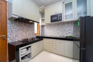 a kitchen with white cabinets and a black counter top at Tempuran Suites By ARBA in Kejayan
