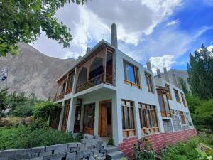 a house with a mountain in the background at The Stone Palace Turtuk in Nubra