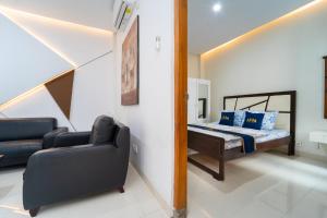 a bedroom with a bed and a couch and a chair at Tempuran Suites By ARBA in Kejayan
