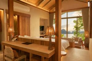 a bedroom with a bed and a desk and a large window at Amber Yao Noi in Ko Yao Noi