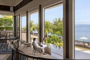 a man and a woman sitting on a porch looking out at the ocean at Dusit Thani Mactan Cebu Resort in Mactan +155 photos