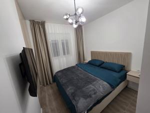 a bedroom with a bed with blue sheets and a chandelier at A&A Apartment in Šušanj