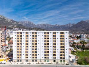 a large white building with mountains in the background at A&A Apartment in Šušanj