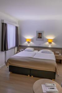 ein Hotelzimmer mit zwei Betten und einem Tisch in der Unterkunft Hotel Francais in Luxemburg (Stadt)
