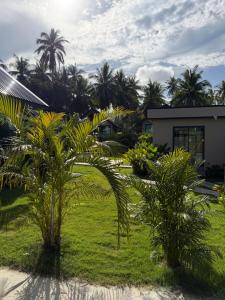 a garden with palm trees and a building at Good Mood Bungalows in Ko Phangan