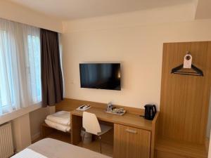 ein Hotelzimmer mit Schreibtisch und Fernseher an der Wand in der Unterkunft Hotel Francais in Luxemburg (Stadt)