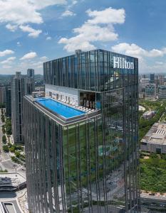 a tall building with a swimming pool on top of it at Hilton Huizhou in Huizhou