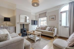 a living room with two couches and a table at Beachcomber, Dog-Friendly Coastal Cottage Close to the Beach in Winterton-on-Sea