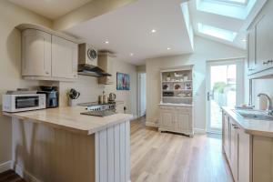 a large kitchen with white cabinets and a large island at Beachcomber, Dog-Friendly Coastal Cottage Close to the Beach in Winterton-on-Sea
