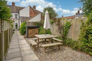 a picnic table with an umbrella and benches at Beachcomber, Dog-Friendly Coastal Cottage Close to the Beach in Winterton-on-Sea