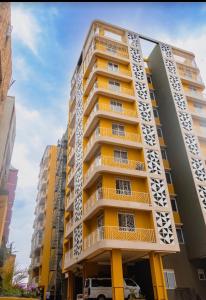 a tall yellow building with balconies on it at Modern 1BR Apartment with Pool & Sauna Kampala in Kira