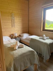 two beds in a wooden room with a window at Domki Sudecka Przystań in Duszniki Zdrój