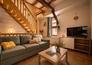 a living room with a couch and a tv at L'Atypique in Eguisheim