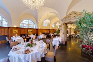 a dining room with white tables and chairs and a chandelier at Schloss Purschenstein in Neuhausen