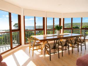 a dining room with a table and chairs and large windows at Grandview Holiday Beach House in Gracetown