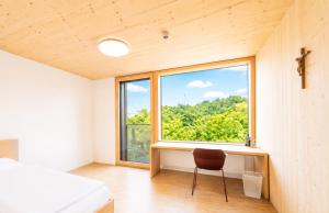 a bedroom with a chair in front of a window at Tagungshotel Kloster Untermarchtal in Untermarchtal +25 photos