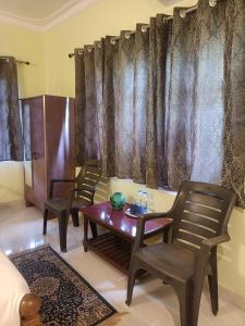 a living room with two chairs and a table at Home Dwarka in Arambol
