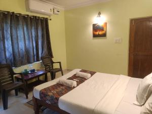 a hotel room with two beds and a table and chairs at Home Dwarka in Arambol