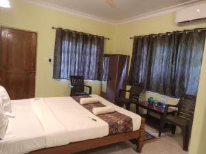 a bedroom with a bed and a table and chairs at Home Dwarka in Arambol