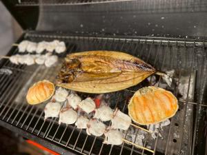 a fish is cooking on a grill at Hotel Asobuba白老 in Shiraoi +13 photos